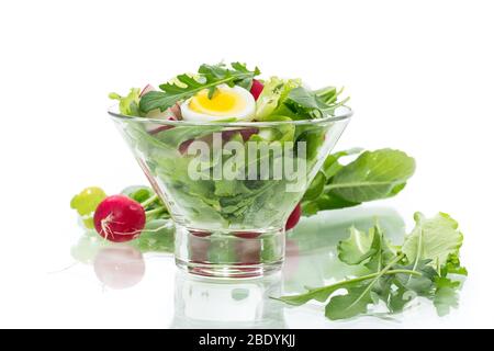 insalata di primavera con rucola, uova sode, rafano fresco, foglie di insalata in una ciotola di vetro Foto Stock