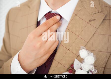 Mani dell'uomo tocca bow tie-in su una tuta Foto Stock