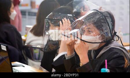 Voto anticipato della Corea del Sud per le elezioni generali del 15 aprile, 10 aprile 2020 : I funzionari elettorali che indossano il plexiglass aspettano di dare guanti di plastica e disinfettanti per le mani agli elettori per prevenire l'infezione da virus in una stazione di scrutinio il primo giorno dei due giorni di voto anticipato per le elezioni generali di Seoul, Corea del Sud, nell'aprile 15. Per prevenire l'infezione da coronavirus COVID-19, agli elettori è stato chiesto di stare a distanza di almeno 1 metro l'uno dall'altro presso le stazioni di raccolta. Si è consigliato di indossare maschere facciali e di lanciare i ballottini dopo aver utilizzato disinfettanti per le mani e indossato guanti. Le elezioni quadreniali Foto Stock