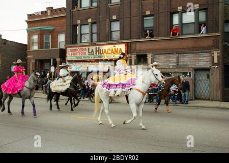 Donne in abiti colorati a cavallo su strada parata, Pilsen, Chicago, Illinois, USA Foto Stock