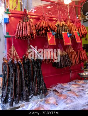 Appendere salsicce secche e prodotti a base di carne in una macelleria. Singapore, Chinatown Foto Stock