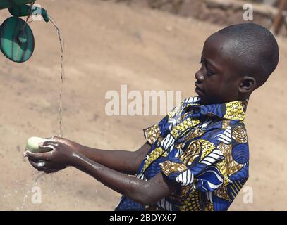 Ritratto all'aperto di ragazzo nero africano mani di lavaggio all'aperto per combattere il virus o i batteri di Coronavirus Foto Stock