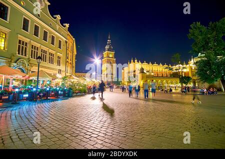 CRACOVIA, POLONIA - 12 GIUGNO 2018: La trafficata piazza del mercato principale di notte, una passeggiata lungo la linea di caffè all'aperto, altri cenare all'interno di loro, il 12 giugno i Foto Stock