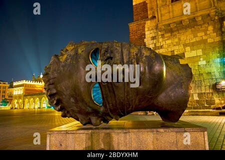 CRACOVIA, POLONIA - 12 GIUGNO 2018: L'illuminazione notturna degli edifici sul mercato principale Sqaure e la scultura moderna Eros Bendato (Eros Bound), il 12 giugno i Foto Stock