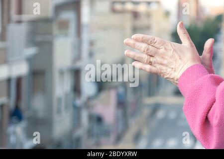 Una donna applaudente dalla sua finestra nel riconoscimento quotidiano di coloro che lavorano contro la pandemia del coronavirus Foto Stock