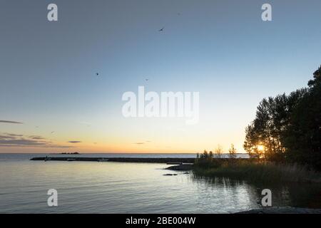 Un molo (molo) nel lago Vänern in Svezia con acque fisse contro un tramonto a metà estate. Foto Stock