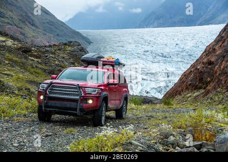 Carrello a quattro ruote motrici rosso su ripida e stretta strada di ghiaia che si affaccia su un ghiacciaio nella lontana Columbia Britannica vicino al territorio di Yukon e Alaska Bo Foto Stock