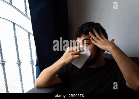 Giovane uomo ispanico con barba che mostra disagio, dolore, malattia, che soffre di sintomi di coronavirus e confinamento, coprendo la bocca e il naso wi Foto Stock