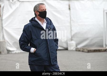 New York, Stati Uniti. 10 aprile 2020. Il sindaco di New York, Bill De Blasio, che indossa una maschera facciale nera, si ferma per un momento dopo aver parlato con gli operatori sanitari al di fuori dell'ospedale temporaneo situato presso l'USTA Billie Jean King National Tennis Center, nel quartiere delle Queens di New York, NY, 10 aprile 2020. Ad aprile 10, il numero globale di morti per coronavirus ha superato i 100,000. (Anthony Behar/Sipa USA) Credit: Sipa USA/Alamy Live News Foto Stock