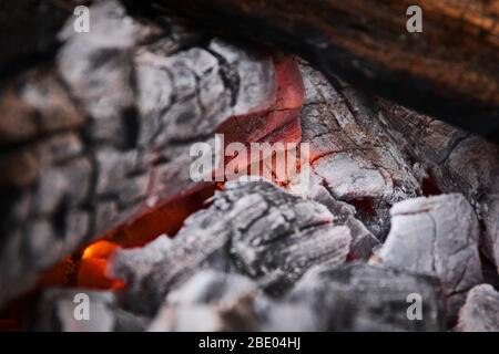 Braci incandescenti al cuore di un fuoco di legna. Fuoco, all'aperto, ambiente rustico. Foto Stock
