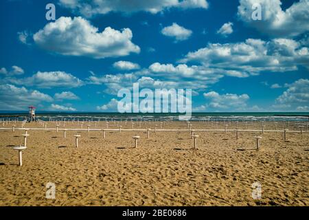 Spiaggia vuota di grado, Italia con molti stand Parasol e cielo blu. Poche nuvole bianche, sabbia arancione. Foto di un giorno di primavera, copyspace Foto Stock