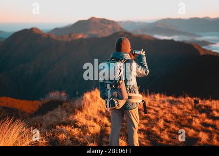 Donna adulta che scatta foto utilizzando il suo cellulare all'alba al Parco Nazionale di Mount Pulag, Benguet, Filippine. Foto Stock