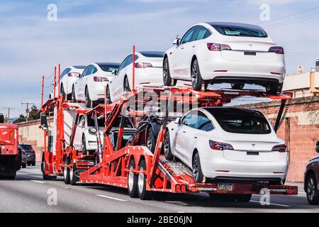 18 gennaio 2020 Palo Alto / CA / USA - il trasportatore di automobili trasporta i veicoli nuovi della Tesla Model 3 su una superstrada nell'area della baia di San Francisco, vista posteriore del rimorchio Foto Stock