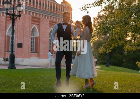 Giovane marito felice sorridente, guardando la moglie dopo il matrimonio all'aperto a Park e andando a Dance. Il bellissimo Summer Park e il tramonto sono a Backgroun Foto Stock