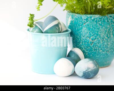 Uova di pasqua fatte in casa blu, verdi, turchesi e bianche colorate con un colore naturale rosso cavolo su sfondo bianco con spazio vuoto decorato. Foto Stock