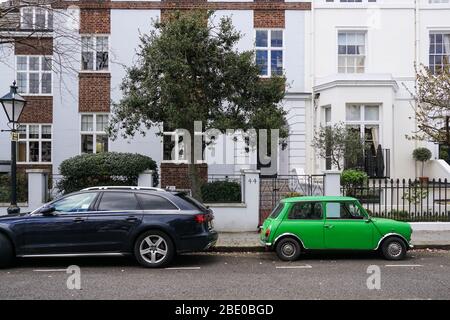 Vecchia auto vintage a due porte Morris Mini Cooper parcheggiata accanto a. Moderna auto Audi A4 Avant di fronte a edifici residenziali Londra Inghilterra Regno Unito Foto Stock