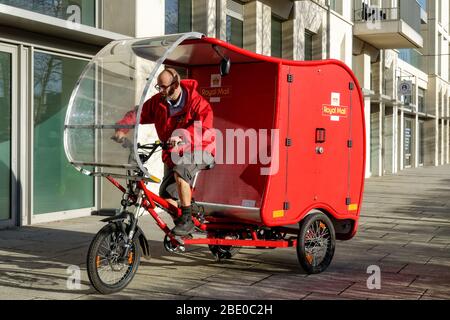 Ciclismo Royal Mail postman su bici elettrica cargo, e-Trike, alimentato da una combinazione di energia solare, batteria, pedale e freno tecnologia Stratford Londra UK Foto Stock