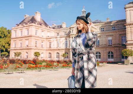 Ragazza felice in un cappello mikimaus nel giardino del Lussemburgo e il Palazzo di Parigi. Il concetto di casa lontano da casa Foto Stock