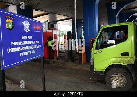 Giacarta, Indonesia. 10 aprile 2020. Gli ufficiali di polizia chiedono ai conducenti di auto che non indossano maschere durante l'imposizione di restrizioni sociali su larga scala quando entrano nell'area di ispezione della capitale al cancello della strada a pedaggio di Giacarta, Indonesia, il 10 aprile 2020. Le autorità della capitale indonesiana hanno iniziato a imporre restrizioni più severe venerdì per rallentare la diffusione del virus corona solo in una città dove la morte del virus è aumentata nella settimana scorsa. Credit: Dasril Roszandi/ZUMA wire/ZUMAPRESS.com/Alamy Live News Foto Stock