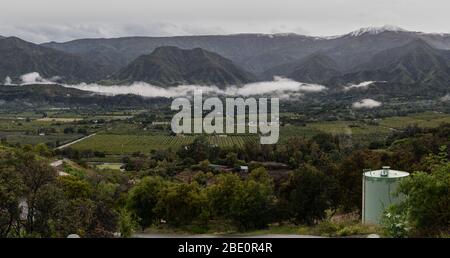 Fertile valle di agricoltura di Ojai, California si trova sotto neve coperta Chiefs Peak cima montagna e nuvole colline. Foto Stock
