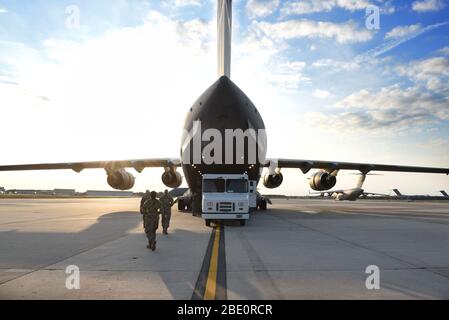 I militari camminano verso un C-17 Globemaster III assegnato alla base dell'aeronautica di Wright-Patterson, Ohio, alla base congiunta McGuire-Dix-Lakehurst, N.J., 5 aprile 2020. Il C-17 trasportò Airmen dall'Ohio e dalla Pennsylvania occidentale che sono in transizione a New York City in sostegno del comando nordico degli Stati Uniti che fornisce il supporto militare per contribuire a combattere la diffusione del COVID-19. (STATI UNITI Foto dell'Air Force di staff Sgt. Stephanie Serrano) Foto Stock