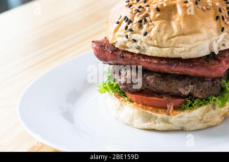 hamburger doppio con pomodoro e lattuga su un piatto bianco Foto Stock