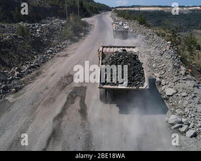 Enorme su strada dumper in cava di pietra caricato trasporto granito colpo dal drone Foto Stock