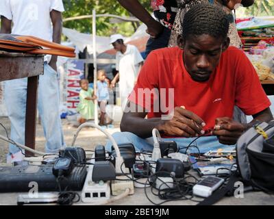 Un profughi haitiani uomo corregge i telefoni cellulari in una tendopoli vicino al Palazzo Presidenziale di Port au Prince, Haiti il 24 gennaio, 2010. Haiti è stata devastata da un terremoto di magnitudine 7.0 a gennaio 12, 2010 . (U.S. Air Force foto di Tech. Sgt. Prentice Colter) (rilasciato) Foto Stock