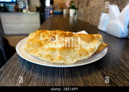 Due cheburks (polpette di carne fritte) su un piatto bianco servito in un caffè. Cucina tradizionale Crimea Tatar Foto Stock