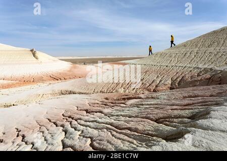 Madre e figlio camminano in bizzarre montagne di gesso, colorate formazioni rocciose di Boszhira in Kazakistancliff occidentale Foto Stock