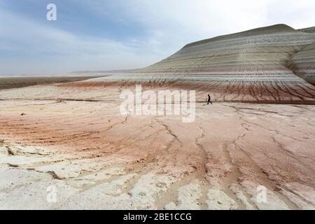 Uomo a bizzarre montagne di gesso, colorate formazioni rocciose di Boszhira in Kazakistancliff occidentale Foto Stock