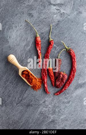 Peperoncino rosso secco e peperoncino in polvere speziato in paletta di legno. Vista dall'alto. Foto Stock