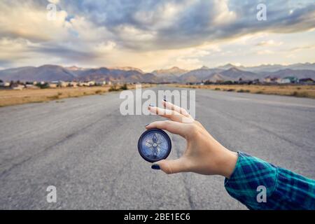 Donna mano nella camicia verde bussola di contenimento a sunrise sullo sfondo del cielo. Viaggi e avventura concetto. Foto Stock