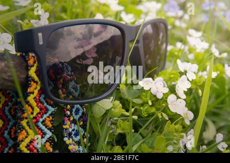 Occhiali da sole sdraiati su un prato primaverile. Natura Foto Stock