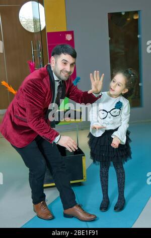 Un illusionista e bambini tiene una colomba nelle sue mani. Il mago mostra una performance . Focus-illusionist mostra i bambini Foto Stock
