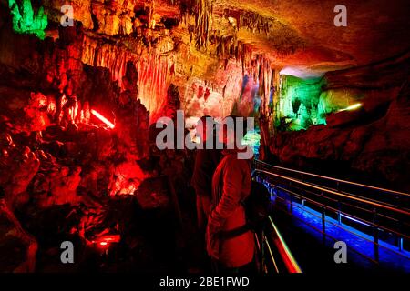 Turista giovane nella grotta sotterranea Sataplia con illuminazione colorata in Kutaisi, Georgia Foto Stock