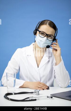 Giovane infermiera femminile in maschera medica con cuffia sulla consultazione del paziente Foto Stock