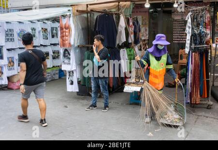 Bangkok, Thailandia - 27 Febbraio 2020: Un pulitore di strada sul lavoro con un vecchio bastone di scopa in via Khaosan, Bangkok, Thailandia Foto Stock