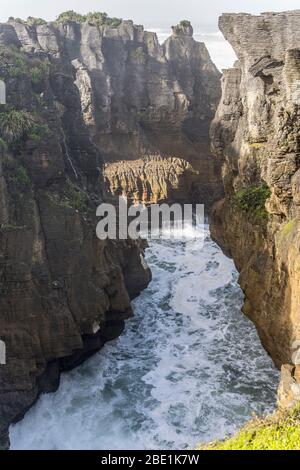 Stretta insenatura tra le scogliere usurate sulla riva, sparato in luce di primavera al parco Pancake Rocks, Punakaiki, West Coast, South Island, Nuova Zelanda Foto Stock