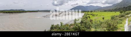 Paesaggio con ciottoli al fiume Wanganui in verde campagna, girato in luce nuvolosa luminosa primavera vicino Harihari, West Coast, South Island, New Foto Stock