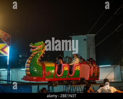 Mumbai, India - 01 dicembre 2019: La famiglia indiana si diverta con un emozionante giro sulle montagne russe al parco divertimenti illuminato di notte Foto Stock