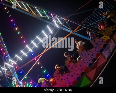 Mumbai, India - 01 dicembre 2019: La famiglia indiana si diverta al parco divertimenti illuminato di notte Foto Stock