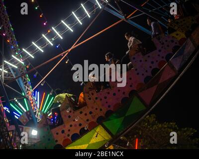 Mumbai, India - 01 dicembre 2019: La famiglia indiana si diverta al parco divertimenti illuminato di notte Foto Stock