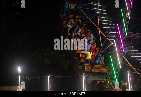 Mumbai, India - 01 dicembre 2019: La famiglia indiana si diverta al parco divertimenti illuminato di notte Foto Stock