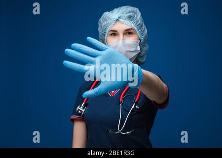 Medico che mostra il segno della mano di arresto in guanto di lattice. Foto Stock