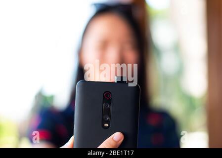 Ragazza che prende un selfie con pop up fotocamera anteriore telefono Foto Stock