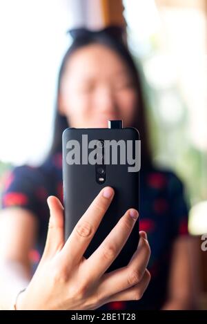 Ragazza che prende un selfie con pop up fotocamera anteriore telefono Foto Stock