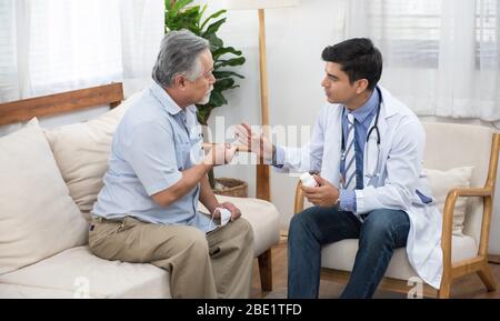 Anziano asiatico senior che chiede al giovane medico caucasico indicazioni e controindicazioni di nuova medicina, sanità e medicina concetto con poliziotto Foto Stock