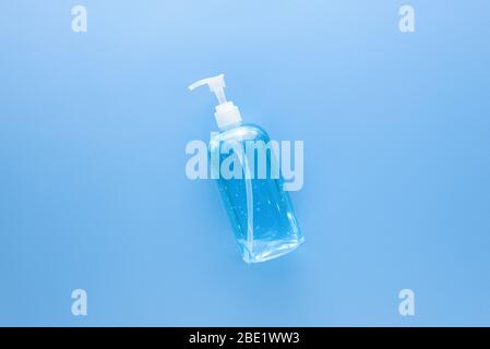 Igienizzante per mani in gel imbevuto di alcol in flacone trasparente per proteggere il medicinale da germi e coronavirus su fondo medico azzurro Foto Stock