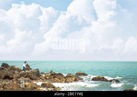 Pescatore che tiene una canna da pesca sulle rocce sul mare a Laem Kho Kwang Beach a Chumphon , Thailandia. 18 marzo 2020 Foto Stock